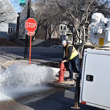 A Public Works employee flushes a fire hydrant
